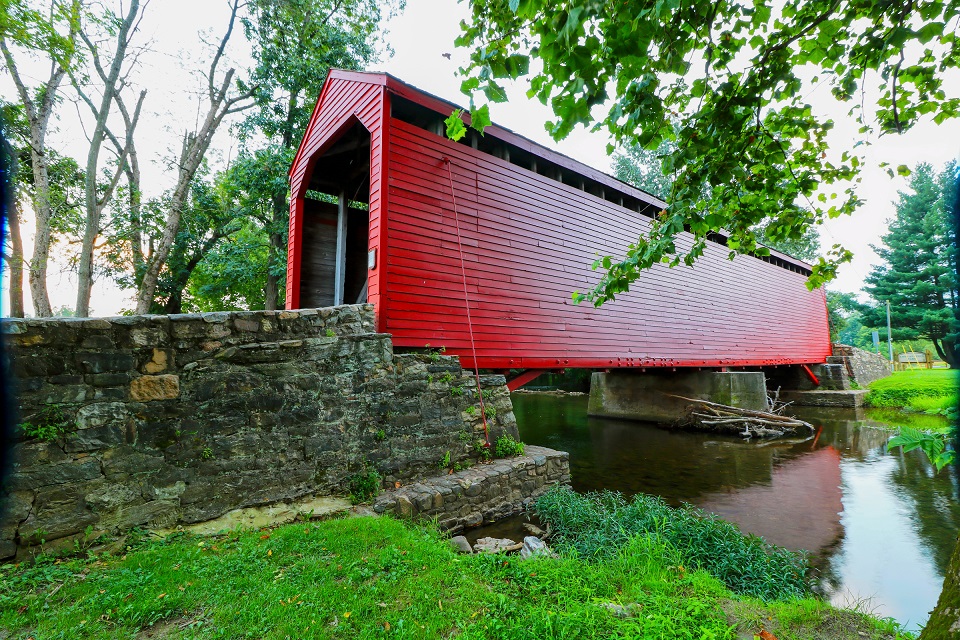 The bright red Roddy Road Covered Bridge spanning a creek near Thurmont, Maryland, USA
