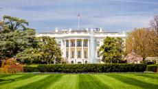 The White House in Washington, DC, USA, in front of a manicured, green lawn on a sunny day.
