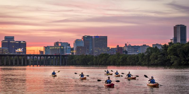 Kayakers float past the city skyline during a pink sunset in Richmond, Virginia, USA