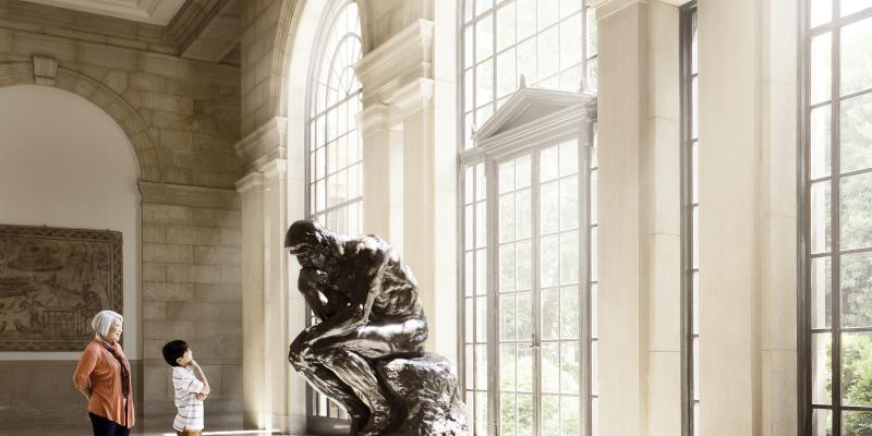 A woman and child looking at Rodin's The Thinker