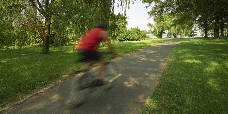 A blurred image of a cyclist riding through the woodlands on the Mount Vernon Trail in Washington, DC, USA