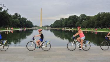 People biking past the Washington Monument on a tour with Bike &amp; Roll in Washington, DC, USA