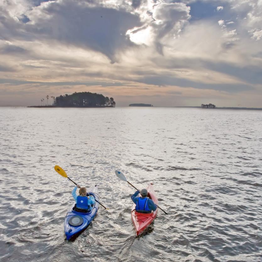 Two people kayak at sunset at Blackwater National Wildlife Refuge in Cambridge, Maryland, USA