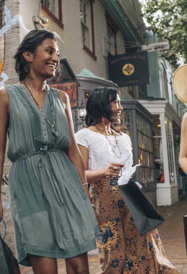 Three women with shopping bags in front of a mural