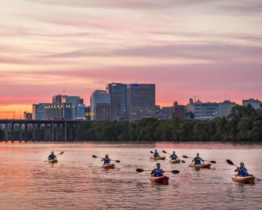Kayakers float past the city skyline during a pink sunset in Richmond, Virginia, USA